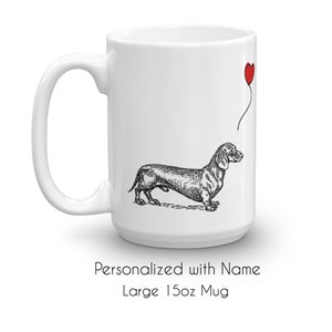 Puede incluir: Taza de cer&aacute;mica blanca con una ilustraci&oacute;n en blanco y negro de un dachshund sosteniendo un globo rojo en forma de coraz&oacute;n. La taza tiene una capacidad de 440 ml y se puede personalizar con un nombre.