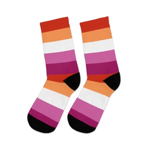 May include: A pair of black socks with a lesbian pride flag design. The socks have red, orange, white, pink, and purple stripes.