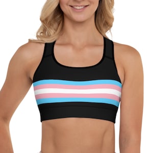May include: Black sports bra with a transgender pride flag design. The flag has horizontal stripes of light blue, pink, white, pink, and light blue.