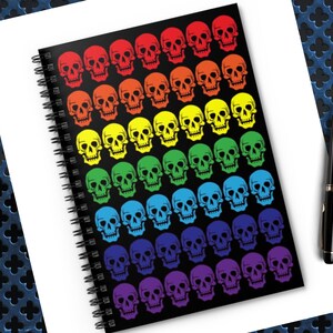 May include: A black spiral notebook with a rainbow pattern of colourful skull designs.