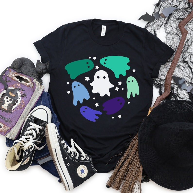 May include: Black t-shirt featuring a design of white and multi-coloured ghosts in a circle. The ghosts are in shades of green, blue, and purple.