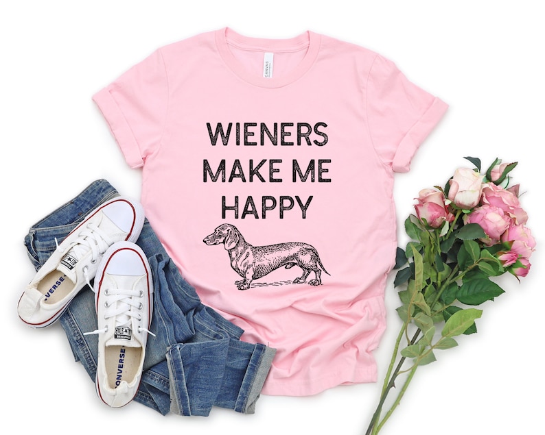 Puede incluir: Camiseta rosa con una ilustraci&oacute;n negra de dachshund y el texto "Wieners Make Me Happy".