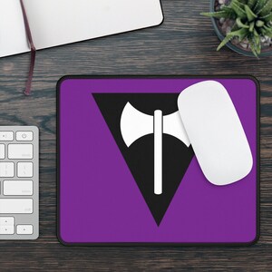 May include: Purple mouse pad with a black triangle and a white axe symbol in the center. The symbol is a common symbol for the lesbian community.