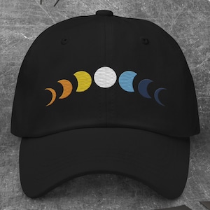 May include: A black baseball cap with an embroidered design of a crescent moon in various phases, including a full moon, in shades of orange, yellow, white, and blue.