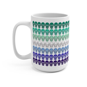 May include: White ceramic mug with a pattern of skulls in shades of green, blue, and purple. The skulls are arranged in rows, with the colors gradually transitioning from green to purple.