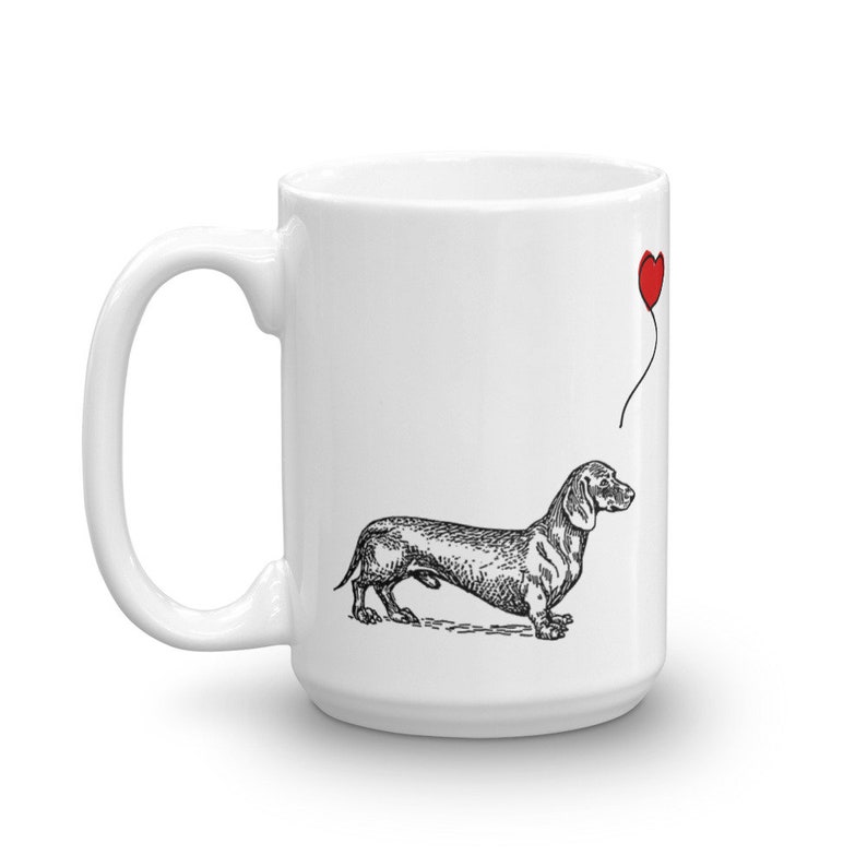 Puede incluir: Taza de cer&aacute;mica blanca con una ilustraci&oacute;n en blanco y negro de un dachshund con un globo rojo en forma de coraz&oacute;n.