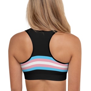 May include: Black sports bra with a transgender pride flag design. The flag has light blue, pink, and white stripes.