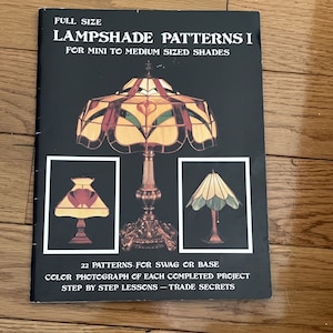Op de afbeelding: Een boek getiteld "Lampshade Patterns I" voor het maken van lampenkappen in mini- tot middelgrote formaten. Het boek bevat 22 patronen voor swag of basis, kleurenfoto's van elk voltooid project en stapsgewijze lessen.