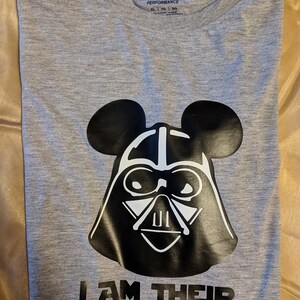 May include: Grey t-shirt featuring a black and white graphic of Darth Vader with Mickey Mouse ears. The text "I AM THEIR FATHER" is printed below the graphic.