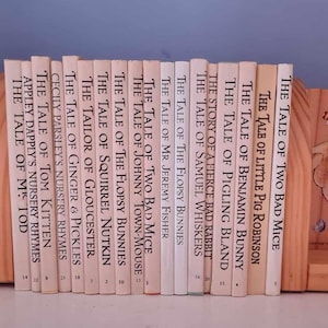 May include: A set of children's books, including "The Tale of Two Bad Mice" and "The Tale of Benjamin Bunny", is held by wooden bookends. The bookends are decorated with rabbit illustrations and the text "Hop Little Rabbit Hop!"