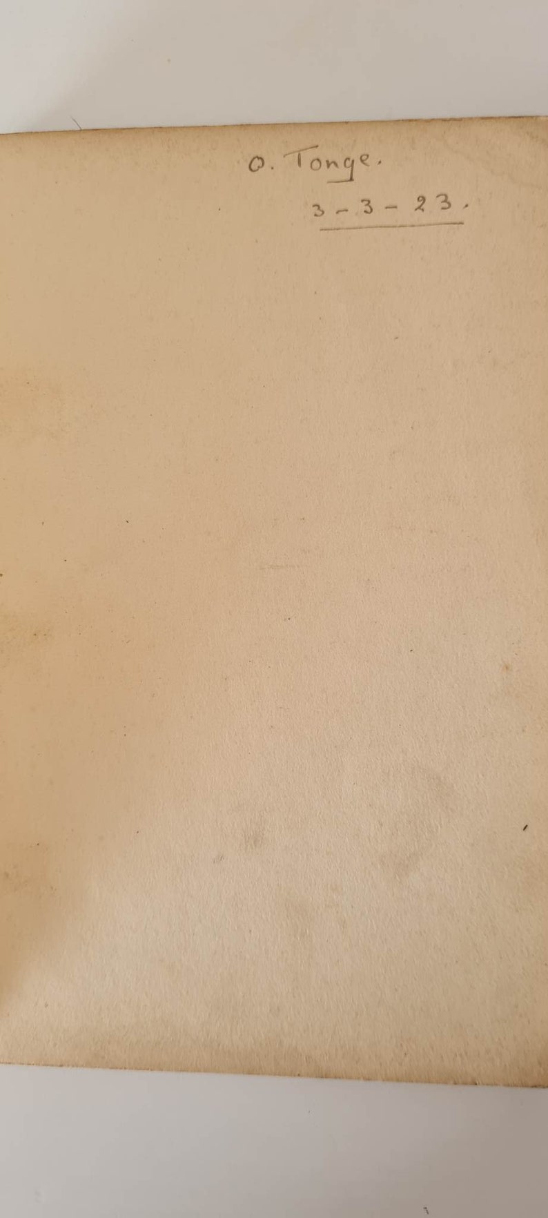 May include: A close-up of a blank, cream-colored page with handwritten text in black ink. The text reads "O. Tonge. 3-3-23."