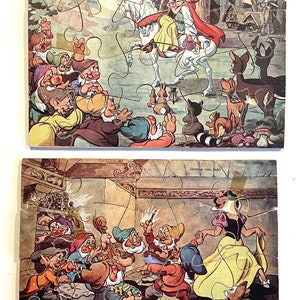 Może przedstawiać: Dwa vintage'owe puzzle przedstawiające sceny z klasycznego filmu Disneya Śnieżka i siedmiu krasnoludków. Pierwsze puzzle przedstawiają Śnieżkę jadącą na białym koniu z księciem, podczas gdy siedmiu krasnoludków obserwuje z lasu. Drugie puzzle przedstawiają Śnieżkę tańczącą z siedmioma krasnoludkami w ich chatce.