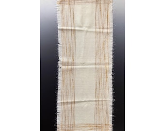 May include: A white table runner with a gold stripe pattern and a frayed edge.