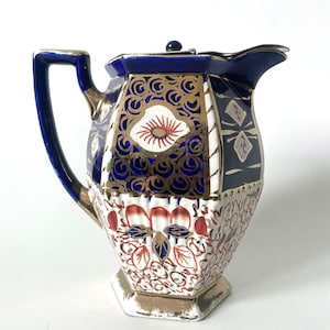 May include: A blue and white ceramic jug with gold accents and floral designs. The jug has a handle and a spout.