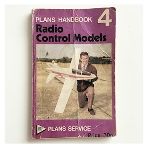 May include: A purple booklet titled "Plans Handbook 4 Radio Control Models" with a photo of a man holding a white and red model aeroplane. The booklet has a price of 30p.