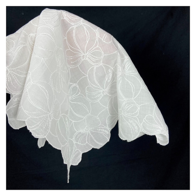 May include: White cotton handkerchief with a delicate floral embroidery design. The handkerchief has a scalloped edge and the word "Ungaro" is embroidered in the corner.