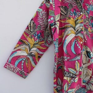 Peut inclure: Un ensemble de pyjama rose vif avec un imprim&eacute; botanique et animalier. Le haut &agrave; manches longues et le pantalon pr&eacute;sentent un motif color&eacute; d'oiseaux, de feuilles et d'autres &eacute;l&eacute;ments de la flore et de la faune. Une bordure blanche souligne les bords du v&ecirc;tement.