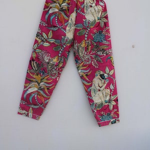 Peut inclure: Un pantalon de pyjama rose avec un imprim&eacute; botanique et singe. Le pantalon a une taille &eacute;lastique et un motif color&eacute; de feuilles, de fleurs et de singes. Le tissu est rose vif avec des accents de blanc, bleu et jaune.