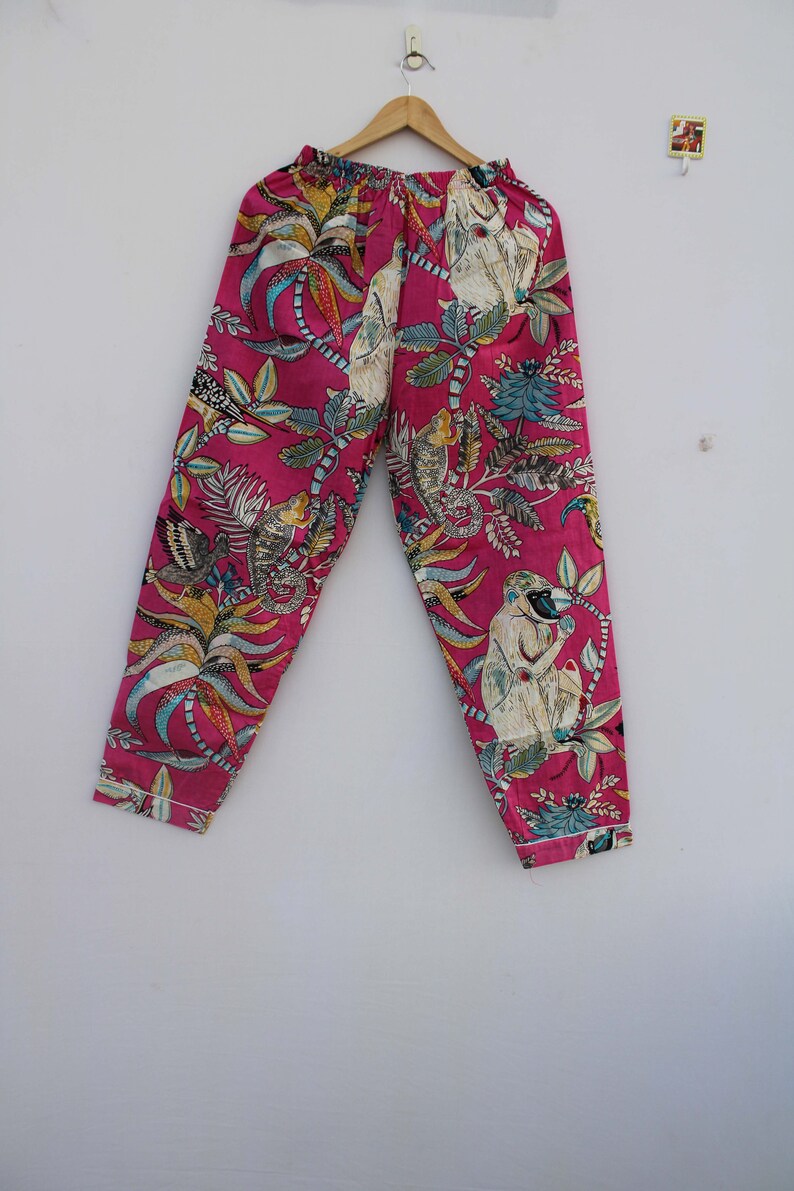 Peut inclure: Un pantalon de pyjama rose avec un imprim&eacute; botanique et singe. Le pantalon a une taille &eacute;lastique et un motif color&eacute; de feuilles, de fleurs et de singes. Le tissu est rose vif avec des accents de blanc, bleu et jaune.