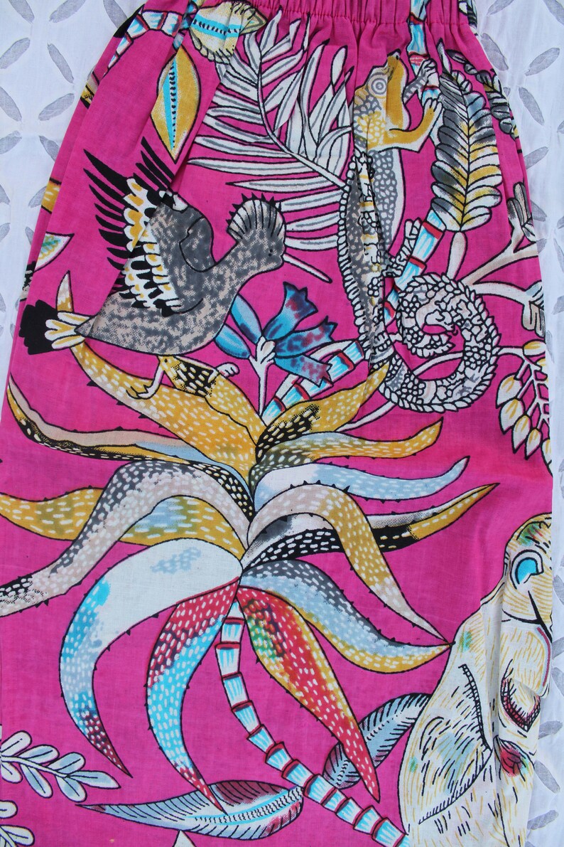 Peut inclure: Tissu rose vif avec un imprim&eacute; tropical repr&eacute;sentant des oiseaux, des palmiers et divers feuillages. Le motif comprend des &eacute;l&eacute;ments jaunes, bleus, blancs et gris, cr&eacute;ant un motif d&eacute;taill&eacute; et color&eacute;. Id&eacute;al pour les v&ecirc;tements ou la d&eacute;coration int&eacute;rieure.