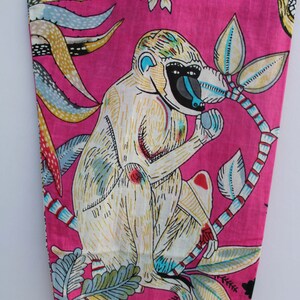 Peut inclure: Tissu rose vif avec une illustration de singe blanc, un visage bleu et un museau noir, tenant un fruit. Le motif comprend des feuilles color&eacute;es et un oiseau sur fond rose.