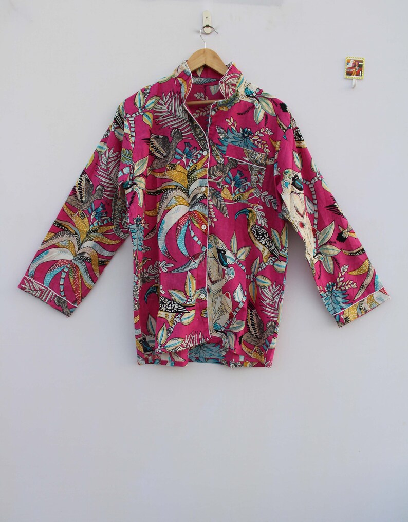 Peut inclure: Un haut de pyjama rose vif avec un imprim&eacute; botanique et d'oiseaux. Le haut &agrave; manches longues pr&eacute;sente une fermeture boutonn&eacute;e, un col crant&eacute; et une bordure blanche. Le tissu est orn&eacute; d'illustrations color&eacute;es d'oiseaux et de feuillage tropical.