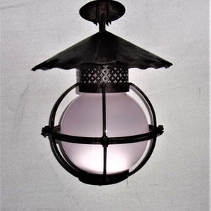 May include: A black metal cage pendant light with a frosted glass globe and a decorative metal top.