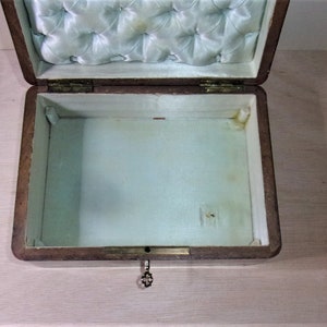 May include: An open wooden box with a light blue satin lining. The box has a keyhole and a small metal key.