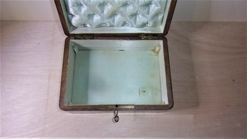 May include: An open wooden box with a light blue satin lining. The box has a keyhole and a small metal key.