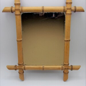 Puede incluir: Un espejo rectangular con un marco de madera natural de bamb&uacute;. El marco est&aacute; hecho de varias piezas de bamb&uacute; que se unen para crear un dise&ntilde;o decorativo. El espejo est&aacute; rodeado por un fino borde negro.