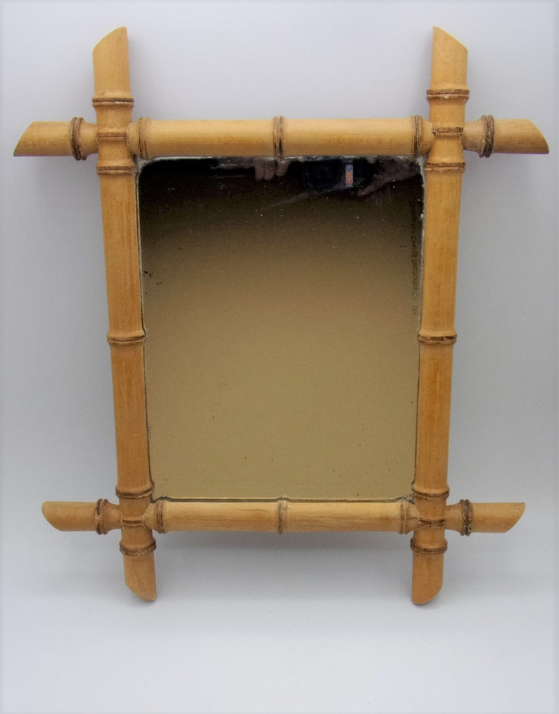 Puede incluir: Un espejo rectangular con un marco de madera natural de bamb&uacute;. El marco est&aacute; hecho de varias piezas de bamb&uacute; que se unen para crear un dise&ntilde;o decorativo. El espejo est&aacute; rodeado por un fino borde negro.