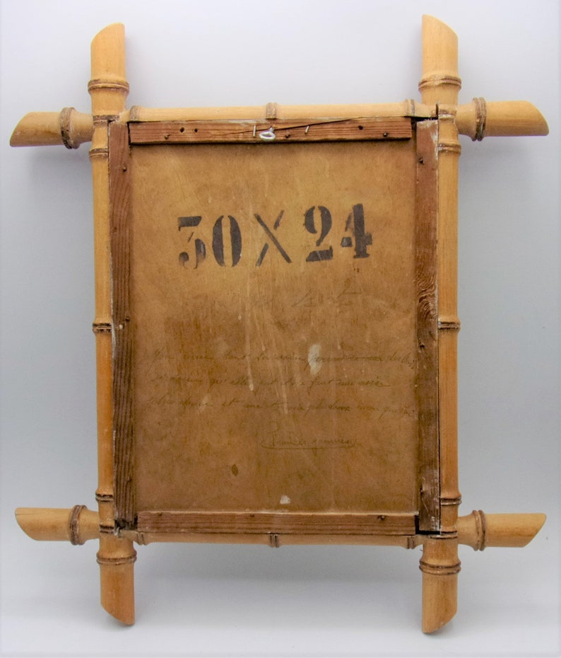 Puede incluir: Un marco de fotos de madera de bamb&uacute; con un respaldo de papel marr&oacute;n. El marco mide 50 x 24 pulgadas y tiene una nota manuscrita en la parte posterior.