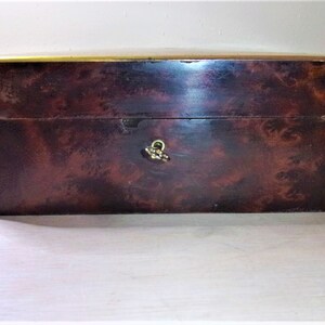 May include: A dark brown wooden box with a brass trim and a brass latch. The box has a wood grain pattern.
