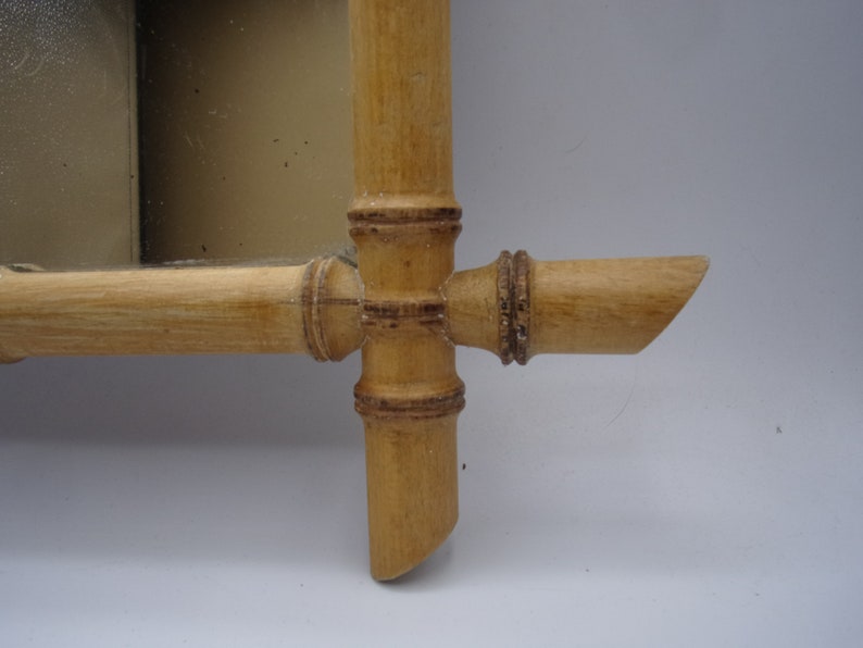 Puede incluir: Primer plano de un marco de espejo de madera hecho de bamb&uacute;. El marco es de color natural y tiene un dise&ntilde;o sencillo.