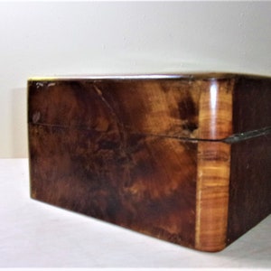 May include: A wooden box with a dark brown finish and a light brown wood trim. The box has a hinged lid and a smooth surface.