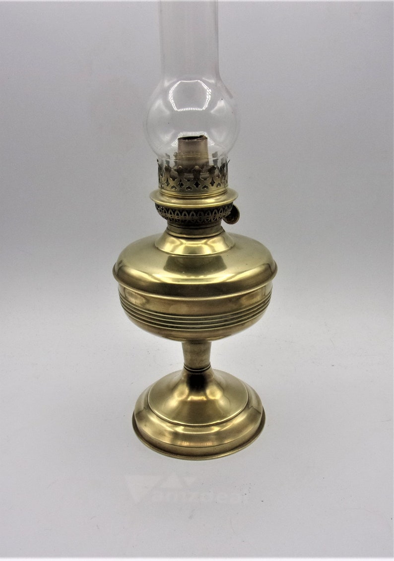 Puede incluir: Una l&aacute;mpara de aceite de lat&oacute;n con una chimenea de vidrio transparente y una base decorativa. La l&aacute;mpara tiene un dise&ntilde;o sencillo y est&aacute; en buen estado.