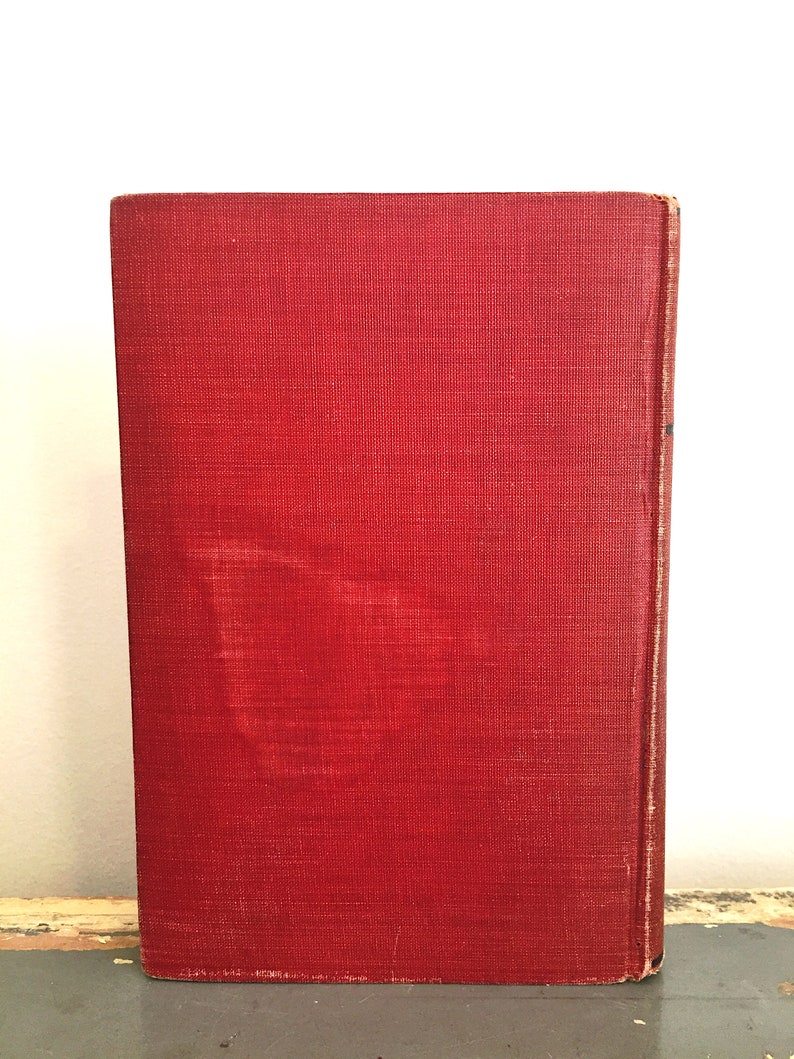 Może przedstawiać: Czerwona książka w twardej oprawie z fakturowaną okładką. Książka leży na drewnianej powierzchni.