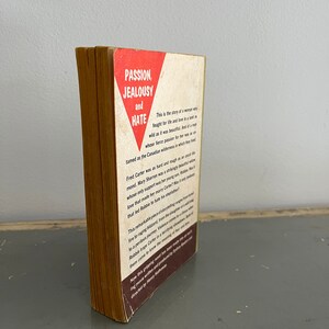 May include: A vintage paperback book with a red triangle on the cover. The title of the book is "Passion, Jealousy and Hate". The text on the back cover describes the story of a woman who fought for life and love in a wild and beautiful land.