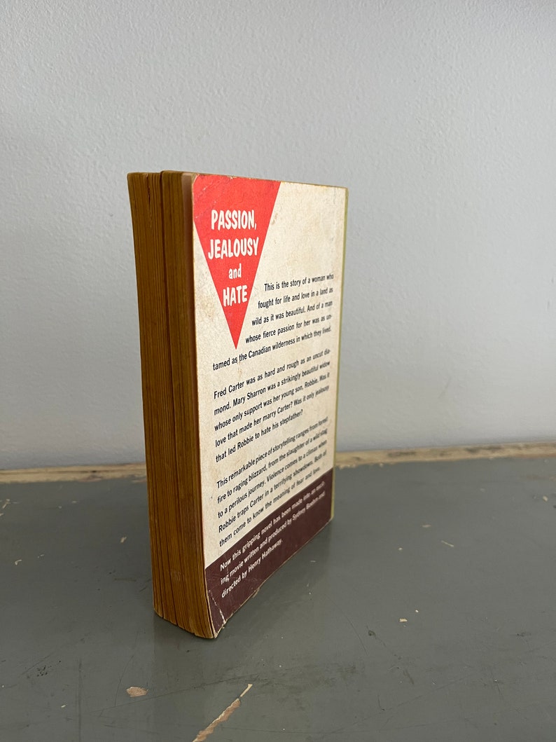 May include: A vintage paperback book with a red triangle on the cover. The title of the book is "Passion, Jealousy and Hate". The text on the back cover describes the story of a woman who fought for life and love in a wild and beautiful land.