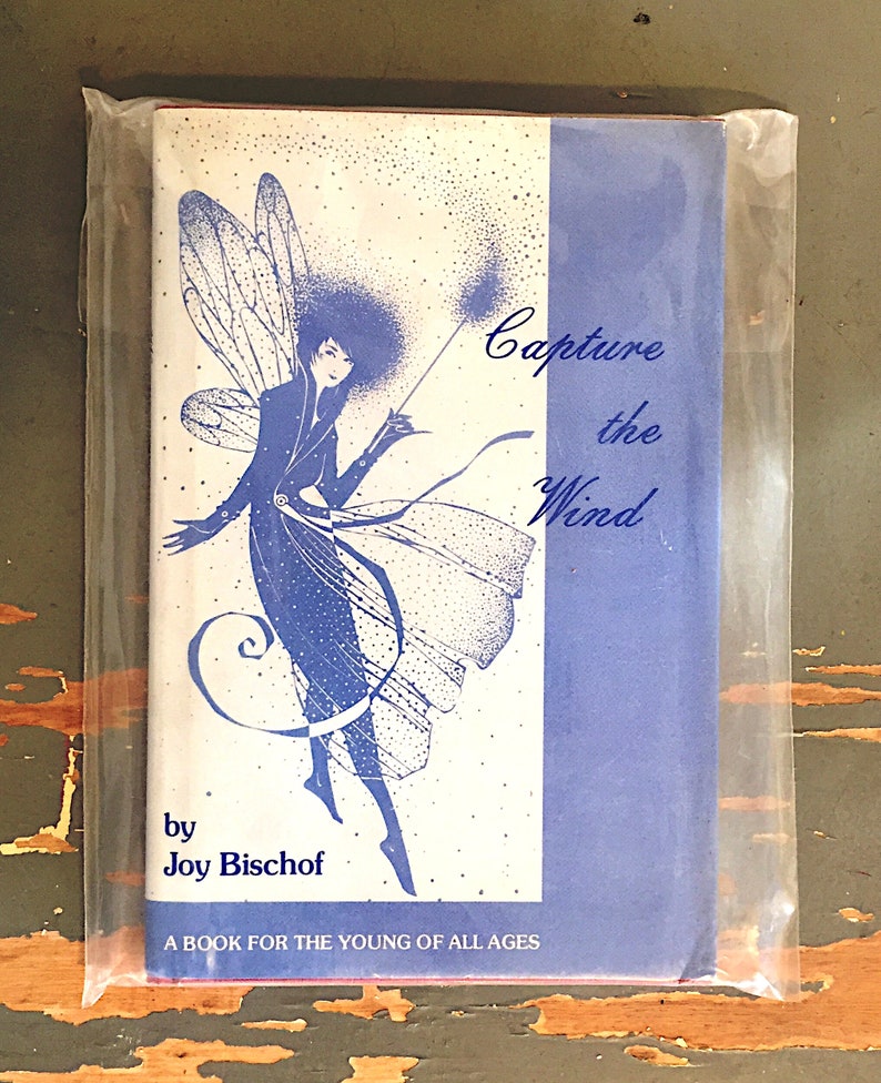 May include: A blue book cover with a fairy illustration and the title "Capture the Wind" by Joy Bischof. The book is for young readers of all ages.
