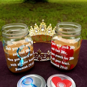 May include: Two glass mason jars filled with a light brown liquid, each with a different colored decal and text from Jeremiah 29:13 and 29:15. The jars are next to a gold crown and two jar lids with magnifying glass designs.