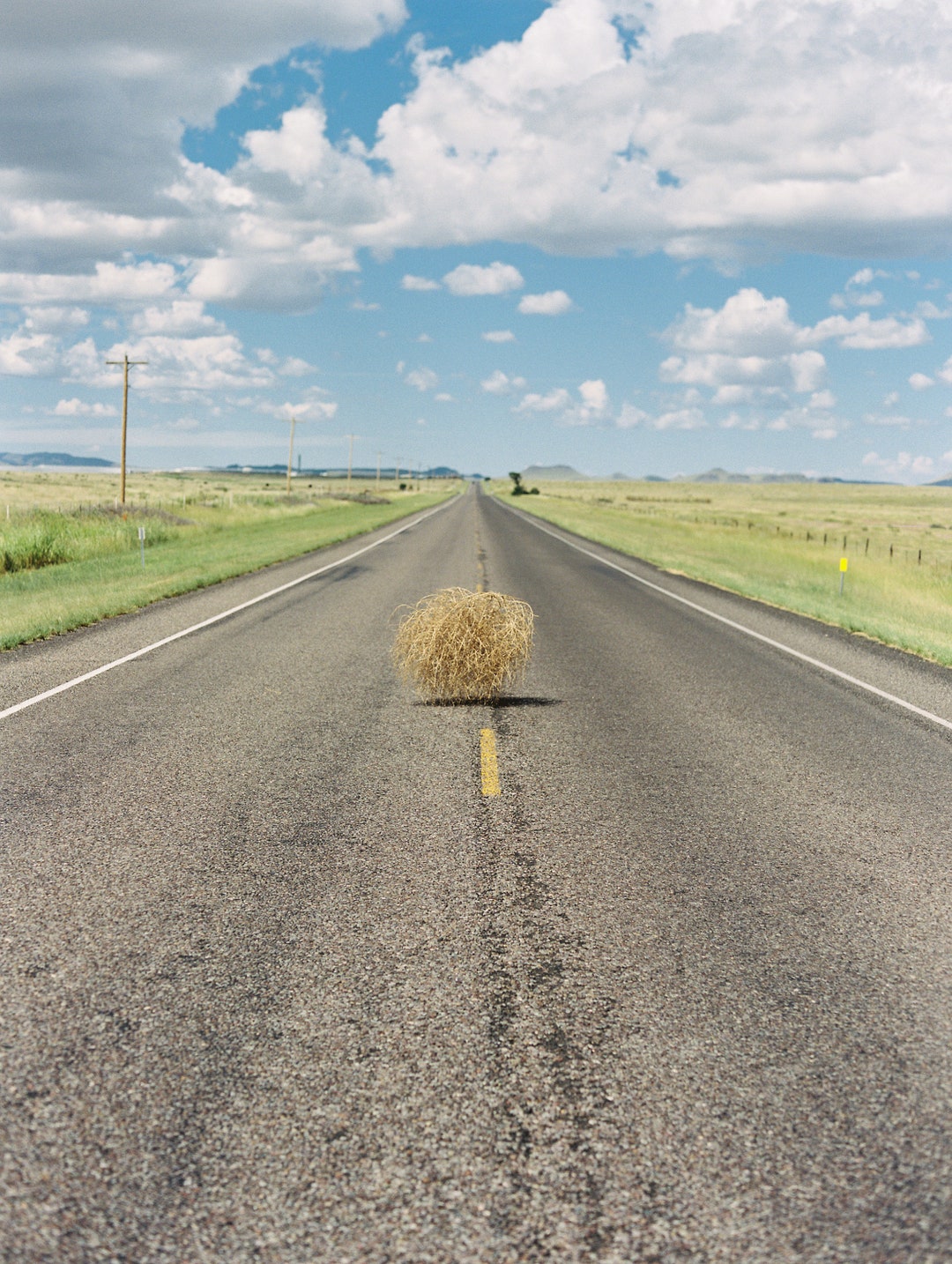 Vertikales Foto von Tumbleweed rollt über West Texas Road West