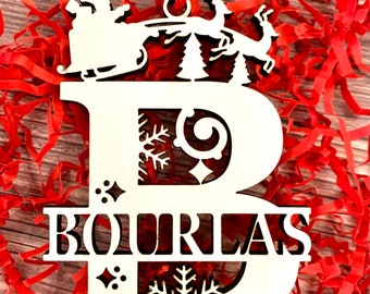 May include: White wooden Christmas ornament shaped like the letter B with a Santa Claus and reindeer design. The ornament has the name "BOURLAS" cut out below the letter.