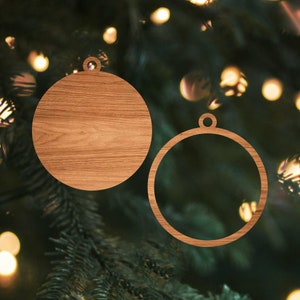 May include: Two wooden Christmas ornaments, one with a natural wood grain finish and the other a plain circle. Both ornaments have a hole at the top for hanging.
