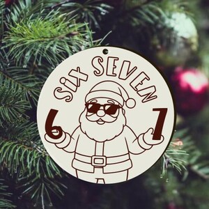 May include: A circular, cream-coloured Christmas ornament with a cartoon Santa Claus wearing sunglasses. The text "SIX SEVEN" is arched above the Santa illustration, with the numbers 6 and 7 on either side. The ornament has a hole for hanging.