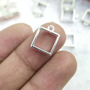 May include: Silver square pendant with a loop at the top. The pendant is empty and can be used for resin or other crafts.