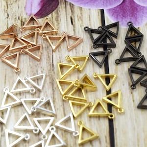 May include: Assortment of triangle-shaped metal charms in gold, silver, and black. The charms have a hole at the top for attaching to jewelry or other crafts.