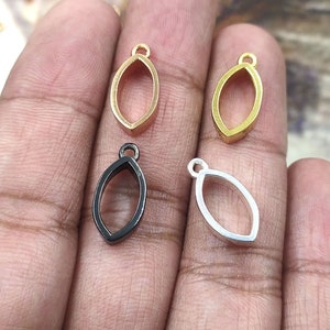 May include: Four metal pendant blanks in different finishes: gold, silver, black, and gold. Each blank is shaped like a teardrop with a loop at the top for attaching a chain or cord.