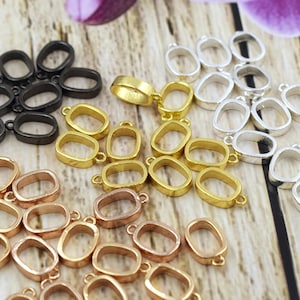 May include: Assortment of oval-shaped pendant bezel settings in black, gold, silver, and rose gold finishes. The bezels are designed to hold a variety of stones or other materials.