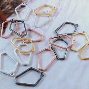 Puede incluir: Una colección de componentes de joyería geométrica de metal en varios colores, incluyendo plata, oro, oro rosa y metal de cañón. Cada pieza tiene una forma única con un pequeño lazo.